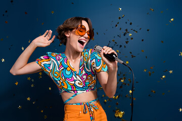 Photo of pretty young girl energetic singer golden confetti dressed stylish flared pants outfit isolated on dark blue color background