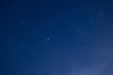 Starry night sky with prominent bright star and cloudy haze