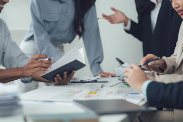Brainstorming and Collaboration: A diverse group of professionals engage in a passionate discussion, meticulously reviewing documents and data as they strategize and collaborate.