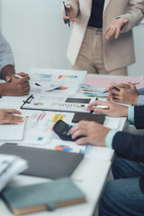 Strategic Business Meeting: Hands-on collaboration around a table strewn with financial documents,...