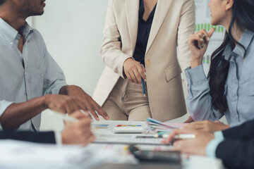 Fototapeta premium Strategic Collaboration: A diverse team of business professionals collaborate around a table in a modern office setting.