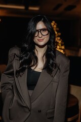 photo of a stylish brunette in glasses against the background of a restaurant interior with blurred...