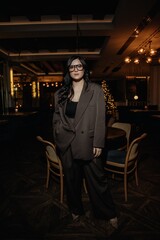 photo of a stylish brunette in glasses against the background of a restaurant interior with blurred...