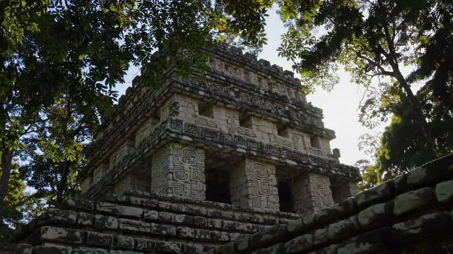 Sunlight illuminating intricate stone carvings and architectural details of a mayan temple at ek balam, partially hidden by dense jungle foliage, evokes ancient mystery and natural beauty