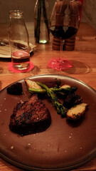 Juicy grilled beef steak nestled beside roasted root vegetables, accompanied by red wine at rustic prague restaurant setting
