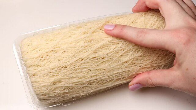 Raw kataifi dough in a package, touch the raw dough with your hands, dessert preparation process