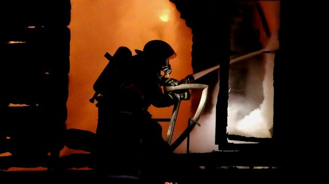 Firefighters extinguish the fire in the house. A strong fire inside the dwelling. A terrible tragedy for people. The night flame inside the home.