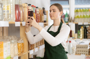 Merchandiser girl takes pictures of goods on supermarket shelves. Checking correct arrangement
