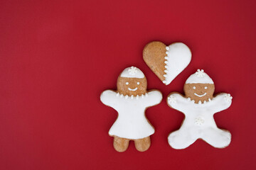 Smiling gingerbread woman, man and heart, red background, copy space for text
