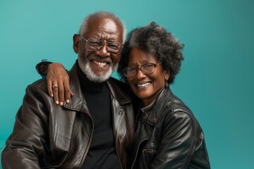 Obraz premium Portrait of a cheerful afro-american couple in their 70s sporting a classic leather jacket isolated in soft teal background