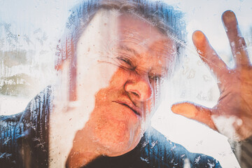 Fototapeta premium Älterer Mann klebt an der Fensterscheibe