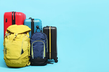 Colorful suitcases and backpacks on light blue background. Space for text