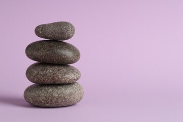 Stack of rocks on lilac background, space for text. Harmony and life balance