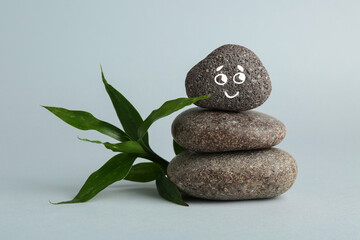 Stack of rocks with drawn smiley face on light grey background. Harmony and life balance