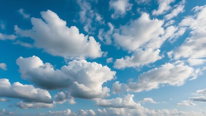 Fototapeta premium A blue sky filled with fluffy white cumulus clouds on a clear winter day. The clouds are scattered across the sky, creating a textured pattern that covers most of the frame.
