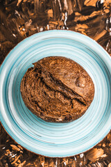 A loaf of rye bread on a turquoise or blue plate on a brown background. Close-up. Top view, Space for text