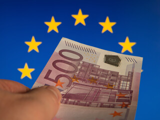 Hand Holding 500 Euro Banknote with European Union Flag Background