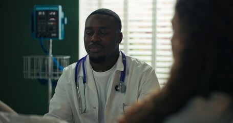 Standing doctor carefully inspects the girl's knee in the hospital room.