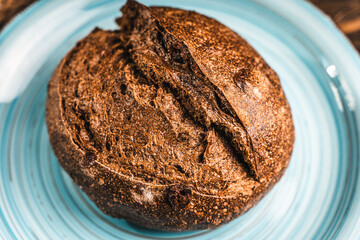 A loaf of rye bread on a turquoise or blue plate on a brown background. Close-up. Top view, Space for text