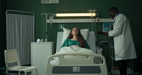 In the hospital ward, the doctor measures the blood pressure of a young girl in bed.