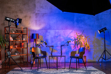 Podcast studio setup featuring microphones and chairs for interviews with vibrant lighting and decorations