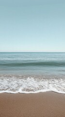 Obraz premium Serene ocean horizon with gentle waves meeting sandy shoreline under clear blue sky