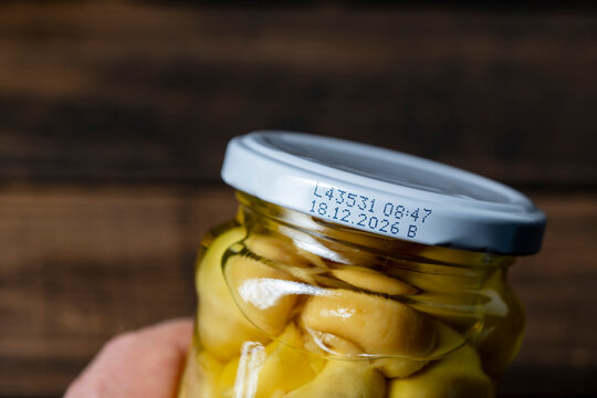 Glass jar of pickled champignon mushrooms with white lid with expiration date, closeup