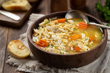 Bowl of chicken noodle soup with carrots on a napkin