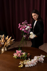 Florist ties a flower arrangement with the ribbon to the order in the flower shop. Making fresh...