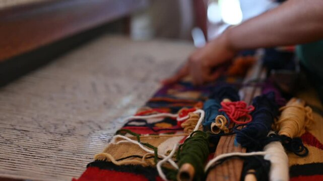 Manos trabajando en un telar artesanal en Teotitlan Oaxaca, tranajo con lana y colores naturales