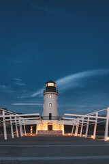Modern lighthouse stands tall, its light piercing the twilight sky, guiding ships along the coastline