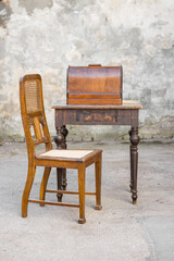 Vintage charm: Antique chair and sewing machine in a weathered outdoor setting.