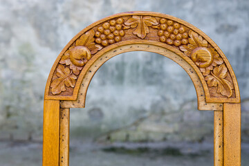 Intricate grape and leaf design carved on a wooden chair backrest, showcasing skilled craftsmanship