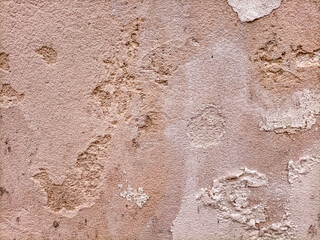  The surface of an old dilapidated wall with peeling off plaster in beige and pink shades. Abstract Background-texture old shabby plaster