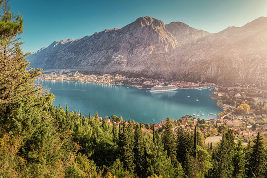 Stunning sunset view of Kotor bay, Montenegro, with a cruise ship docking and the mountains in the background