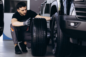 Car mechanic changing tires in car service salon