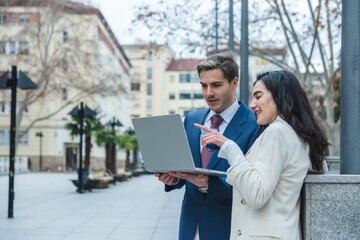Businesspeople working with laptop outdoors in urban environment