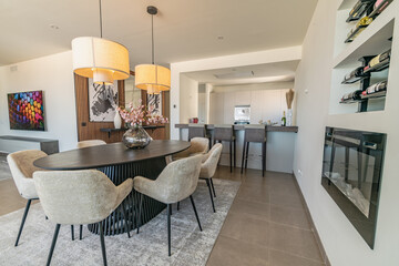 a close up indoor image of a dining table next to fireplace in front of an open kitchen in Mediterranean apartment 