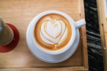 Heart shaped hot latte crafted in ceramic cup on wooden tray in coffee shop