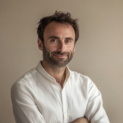 Obraz premium Man with beard smiles while standing with arms crossed in a neutral-toned room during daylight hours. Generative AI