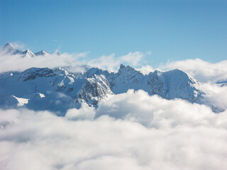 Low clouds leaving only the peaks of the snowy mountain tops visible in the winter on a sunny cold day with a clear blue sky