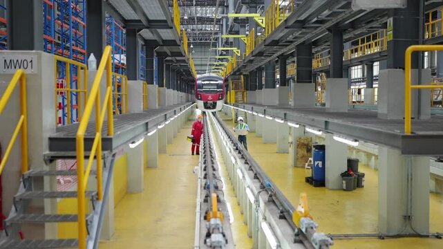Inside Train Maintenance Depot: A spacious and brightly lit train maintenance depot, featuring multiple tracks and a lone worker in red overalls.