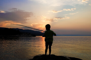 Fototapeta premium happy child fishing by the sea silhouette