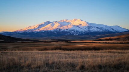 Obraz premium Majestic Snow-Capped Mountain Under Clear Blue Sky at Sunset