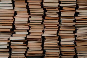 A stack of books is piled high, with some of them being old and worn
