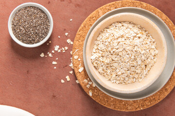 A healthy breakfast featuring oats in a bowl on a cork mat, accompanied by chia seeds, showcasing a rustic and wholesome meal
