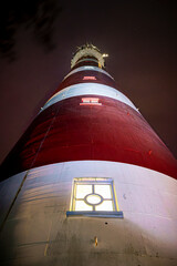 Majestic high up view of red with white striped lighthouse on Dutch Wadden Island at night time with stormy weather