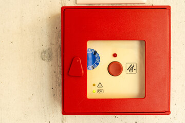 Red fire alarm box on the wall. Service badge inside.