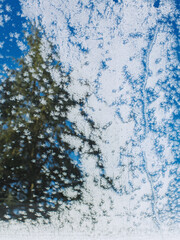 Blick durch Fenster bei Schnee und blauen Himmel mit Eiskristallen am Glas
