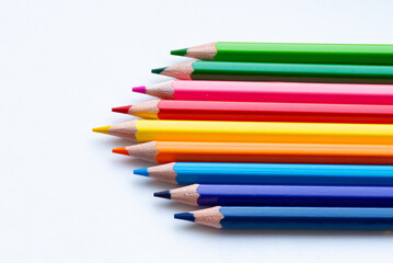 A vibrant array of colored pencils neatly arranged in a row, showcasing a spectrum of colors against a clean, white background.
